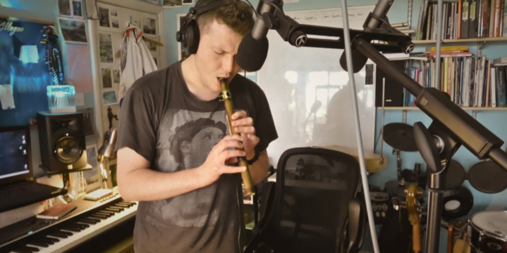 Untitled design Studio action shot of Felix performing on bamboosax in front of two microphones.